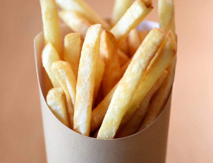 Portion of crispy deep fried golden potato chips or French fries served in a container
