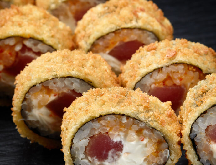 Hot fried sushi roll with salmon. Sushi menu. Japanese food. Hot fried sushi roll on black background.