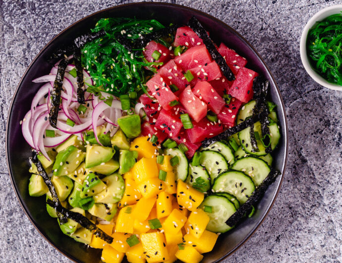 Hawaiian tuna poke bowl with seaweed, avocado, mango, cucumber, top view.